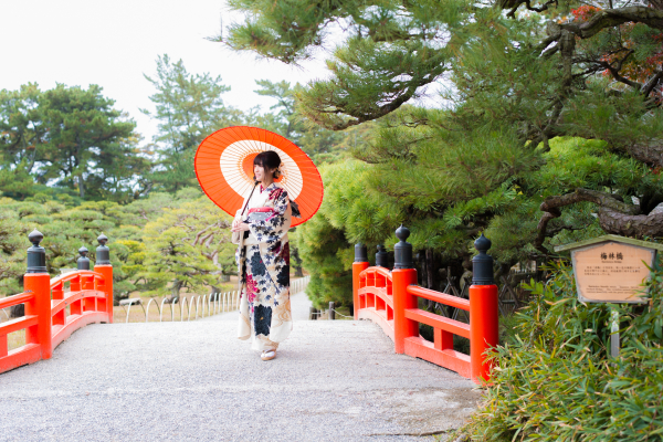 着物を着た女性が和傘をさして橋を歩いている様子